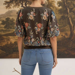 graced Brenda floral top in brown with puff sleeves and ribbed waist, worn by a woman from the back view