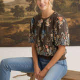 graced Brenda floral top in brown with puff sleeves and ribbed waist, worn by a model with light blue jeans