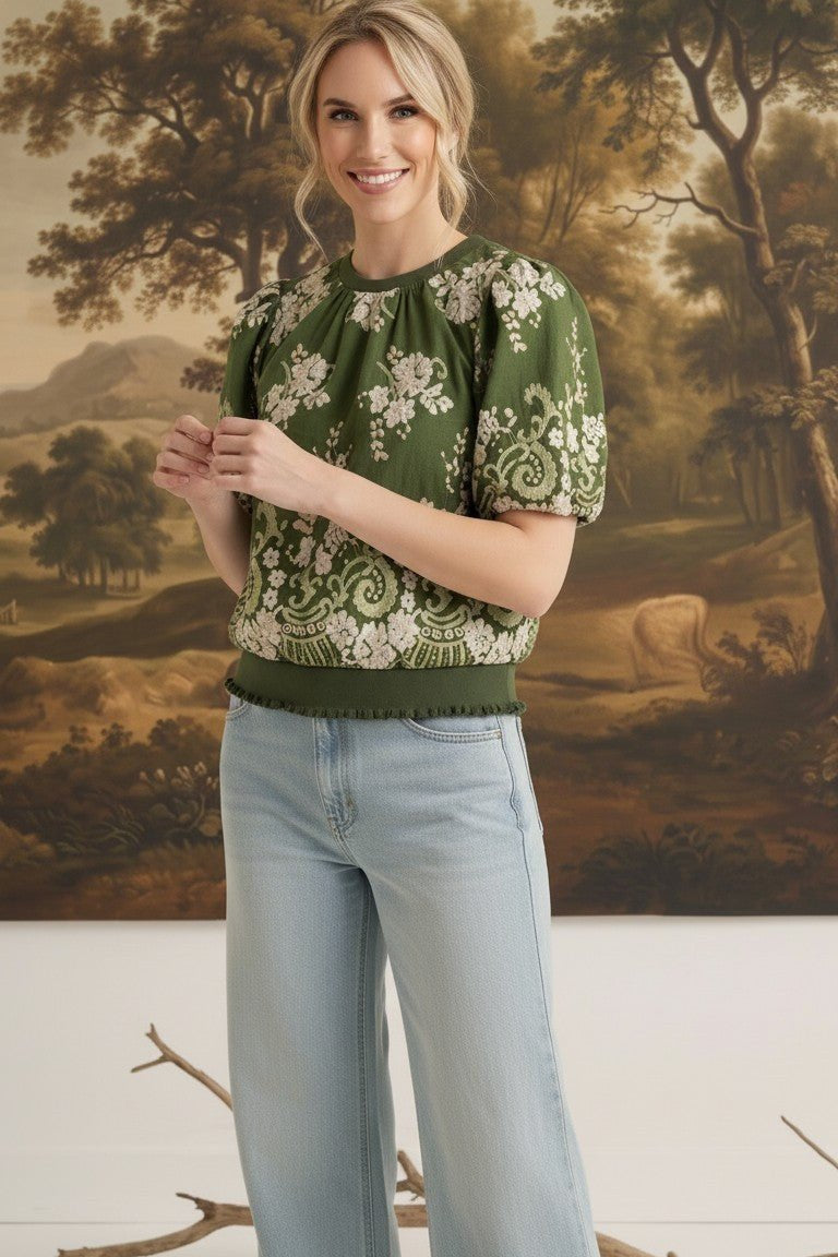 Model wearing graced Brenda olive green floral top with puff sleeves and ribbed waist, paired with light wash jeans.