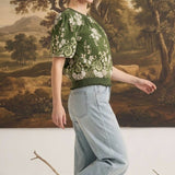 graced Brenda floral top in olive with puff sleeves and ribbed waist, worn by a model with light wash jeans
