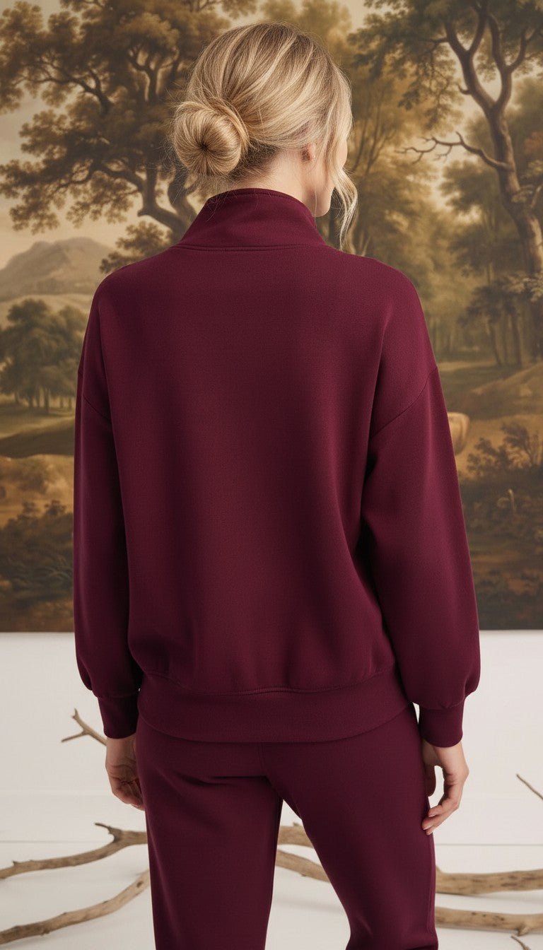 Back view of a woman wearing a graced dark cherry ribbed quarter-zip sweater with a relaxed fit and long sleeves.