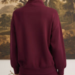 Back view of a woman wearing a graced dark cherry ribbed quarter-zip sweater with a relaxed fit and long sleeves.