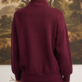 Back view of a woman wearing a graced dark cherry ribbed quarter-zip sweater with a relaxed fit and long sleeves.