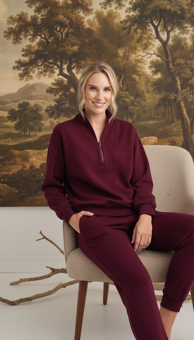 graced Brooklyn Rib quarter zip sweater in dark cherry worn by a smiling woman sitting on a chair