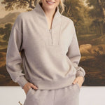 A woman wearing a graced heather taupe ribbed quarter-zip sweater with a relaxed fit and matching lounge pants.