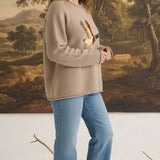 graced Carley Mallard sweater in mocha featuring a mallard duck graphic, worn by a model with blue jeans