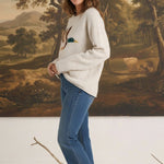 Model wearing graced The Carley Mallard Sweater in oatmeal with a mallard duck graphic, paired with blue jeans.
