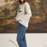Model wearing graced The Carley Mallard Sweater in oatmeal with a mallard duck graphic, paired with blue jeans.