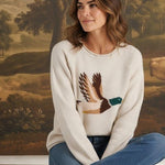 Model wearing graced Carley Mallard oatmeal knit sweater with duck graphic, blue jeans, and beige loafers.