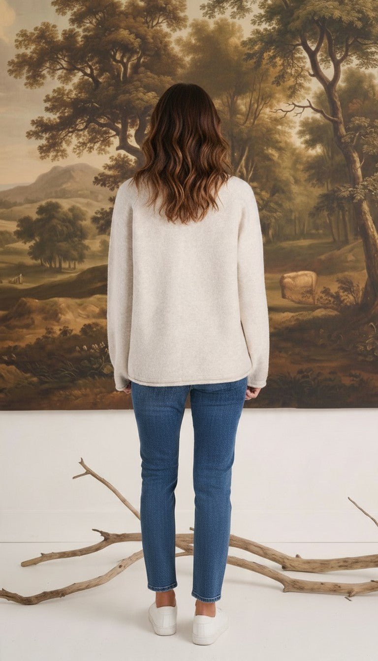 Back view of a woman wearing a graced Carley Mallard oatmeal sweater with blue jeans and white sneakers