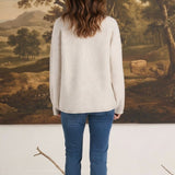 Back view of a woman wearing a graced Carley Mallard oatmeal sweater with blue jeans and white sneakers