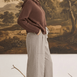 A woman wearing graced Carly mixed stripe wide leg pants in beige and brown, paired with a brown hooded sweater.