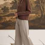 graced model wearing brown zip-up sweater and mixed stripe wide leg pants in a studio setting