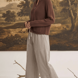 graced model wearing brown zip-up sweater and mixed stripe wide leg pants in a studio setting