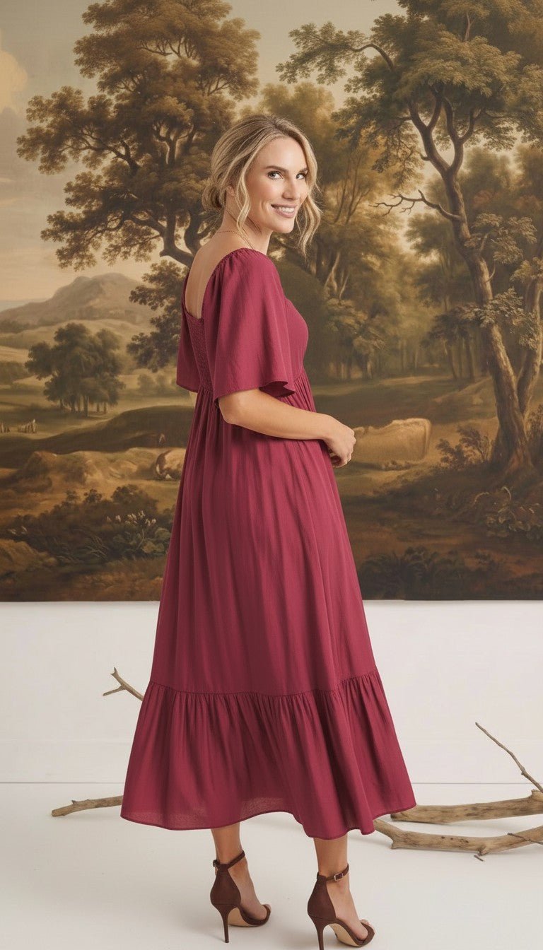 graced Celeste midi dress in deep berry with puff sleeves and a tiered skirt worn by a model in a studio setting