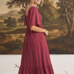 graced Celeste midi dress in deep berry with puff sleeves and a tiered skirt worn by a model in a studio setting