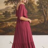 graced Celeste midi dress in deep berry with puff sleeves and a tiered skirt worn by a model in a studio setting