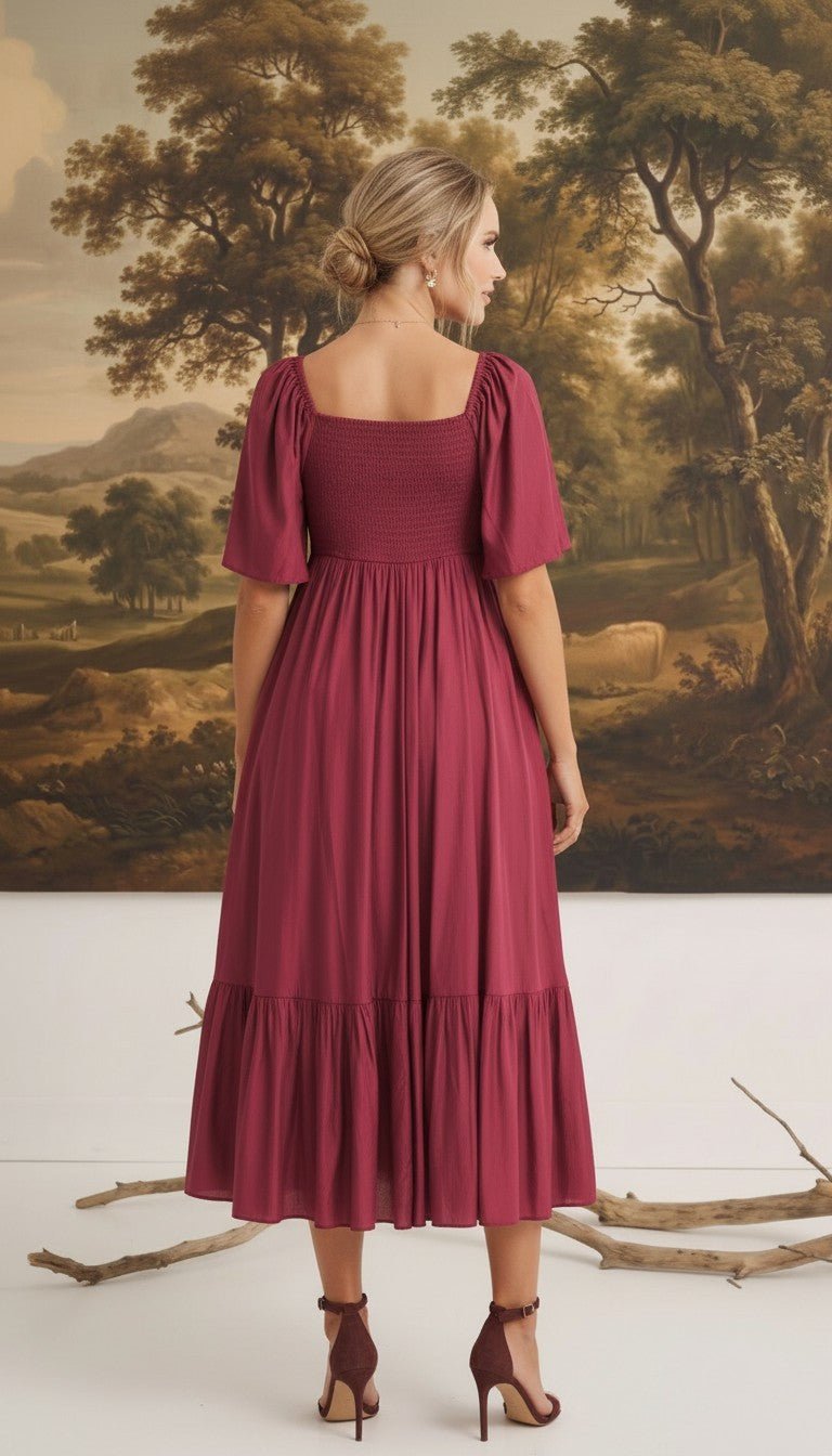 Back view of a woman wearing a graced Celeste puff sleeve midi dress in deep burgundy with a smocked bodice.