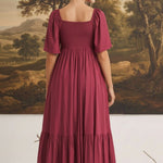Back view of a woman wearing a graced Celeste puff sleeve midi dress in deep burgundy with a smocked bodice.