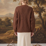 Back view of a model wearing a mocha chunky knit cardigan by graced, featuring a textured pattern and relaxed fit.