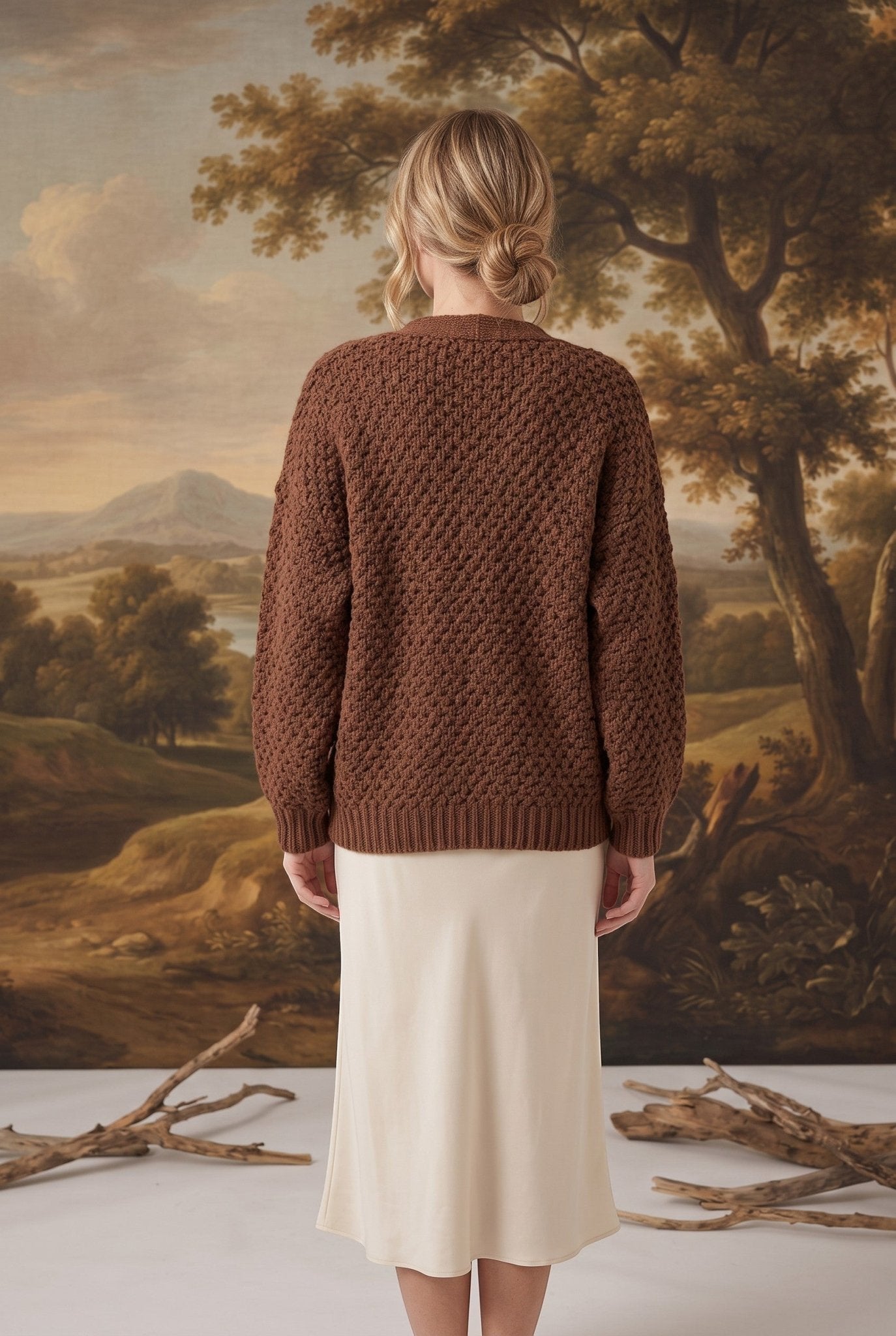 Back view of a model wearing a mocha chunky knit cardigan by graced, featuring a textured pattern and relaxed fit.