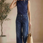 graced The Cinch Side Top in navy cotton worn by a blonde model with wide-leg jeans and a straw tote bag