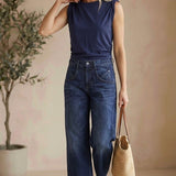 graced The Cinch Side Top in navy cotton worn by a blonde model with wide-leg jeans and a straw tote bag