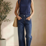 graced The Cinch Side Top in navy cotton worn by a model with dark wash jeans and a straw tote bag