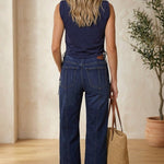 graced navy cotton sleeveless top with side tie detail worn by a woman with dark denim jeans and a straw tote bag