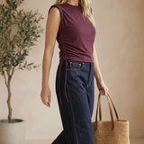 Model wearing a graced winetasting cotton top with side tie detail and sleeveless silhouette with dark denim jeans