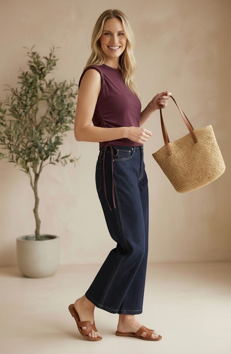 graced The Cinch Side Top in winetasting cotton with side tie detail worn by a smiling woman with dark denim jeans