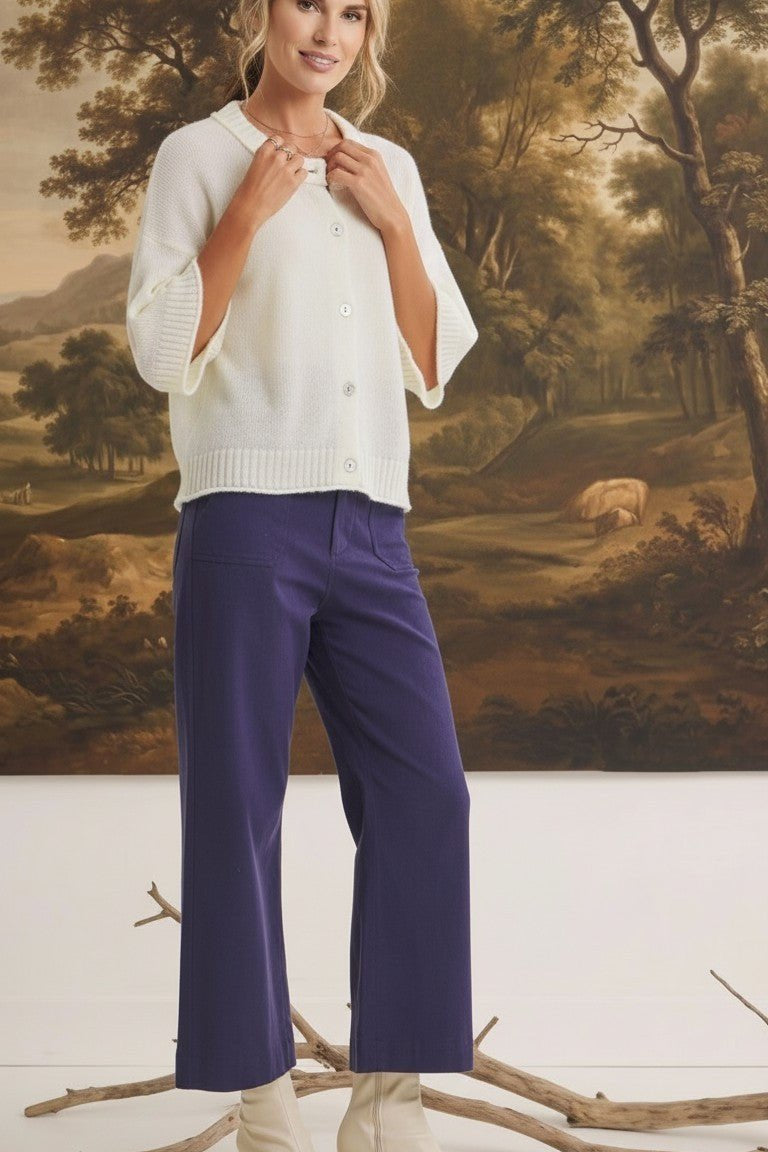 Model wearing graced navy wide-leg Darcy pants with pocket details and a white button-up cardigan