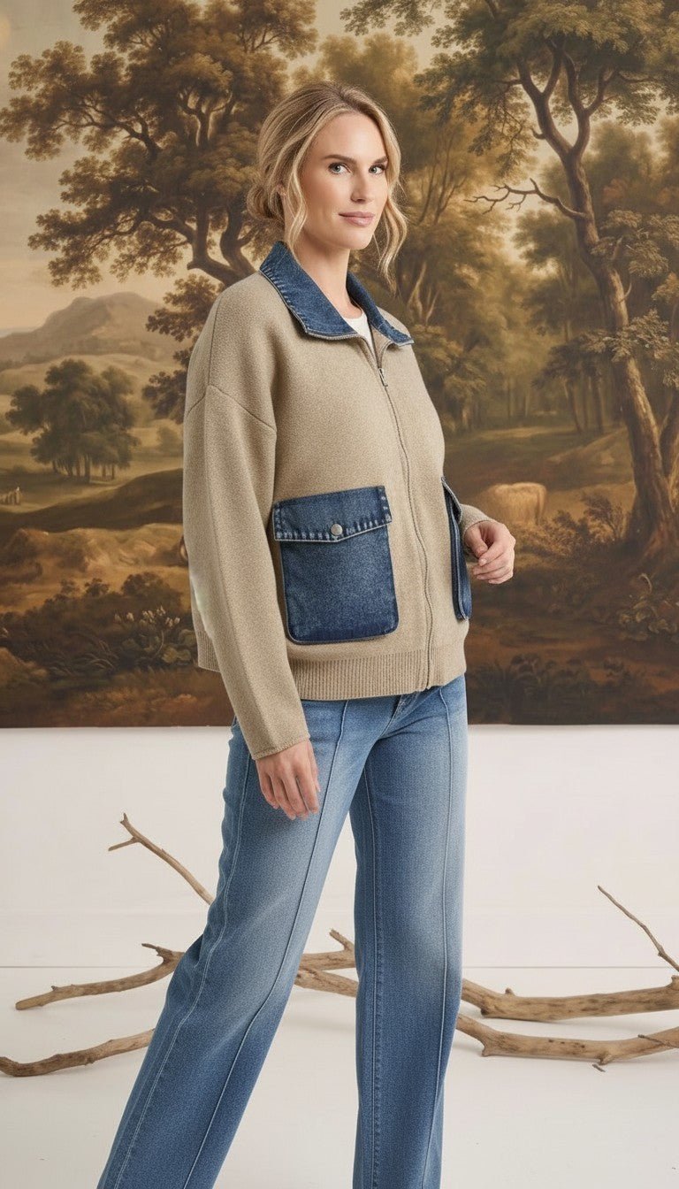 Model wearing graced taupe zip-up sweater jacket with denim collar and pocket details against a landscape backdrop.
