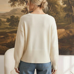 Back view of a woman wearing a graced ivory crew neck sweater with dropped shoulders and wide ribbed hem and cuffs.