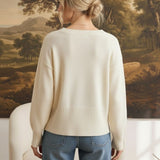 Back view of a woman wearing a graced ivory crew neck sweater with dropped shoulders and wide ribbed hem and cuffs.