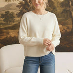A woman wearing a graced ivory Eloise crew neck sweater with dropped shoulders and wide ribbed cuffs and hem.