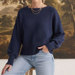 Model wearing a navy graced Eloise crew neck sweater with dropped shoulders and wide ribbed cuffs, paired with jeans.