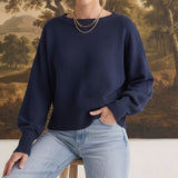 Model wearing a navy graced Eloise crew neck sweater with dropped shoulders and wide ribbed cuffs, paired with jeans.