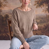 A woman wearing a graced taupe crew neck sweater with drop shoulders and ribbed hem, styled with light wash jeans.
