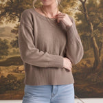 Model wearing a taupe graced Eloise crew neck sweater with drop shoulders and wide ribbed cuffs and hem.