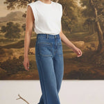 Model wearing graced Emerson relaxed flare jeans with patch pockets and a white sleeveless top in a studio setting