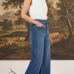 Model wearing graced The Emerson Patch Pocket Relaxed Flare Jeans in medium wash denim with a white sleeveless top.