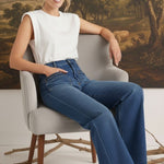 graced Emerson relaxed flare jeans with patch pockets worn by a model in a white sleeveless top sitting on a chair