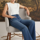 graced Emerson relaxed flare jeans with patch pockets worn by a model in a white sleeveless top sitting on a chair