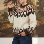 A model wearing a graced Fair Isle cable knit sweater in cream and brown with a round neck and long sleeves.