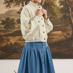 graced cream cotton blend jacket with balloon sleeves worn by a model in front of a landscape painting