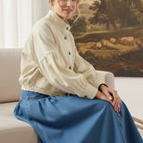 graced cream cotton balloon sleeve jacket worn by a woman sitting on a sofa with a blue denim skirt