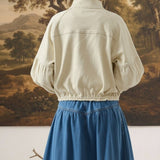 Back view of a model wearing the graced Jaden cream cotton balloon sleeve jacket with a blue denim skirt