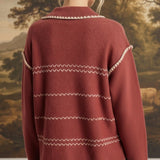 Back view of a woman wearing the graced Jenna Whipstitch Sweater in rust red with cream contrast embroidery details.