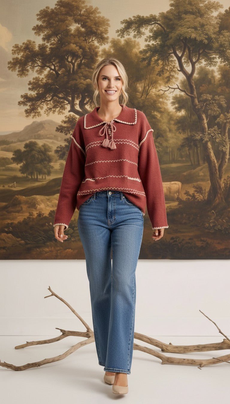 graced Jenna Whipstitch Sweater in rust red with contrast embroidery, collar, and tassel detail worn with blue jeans
